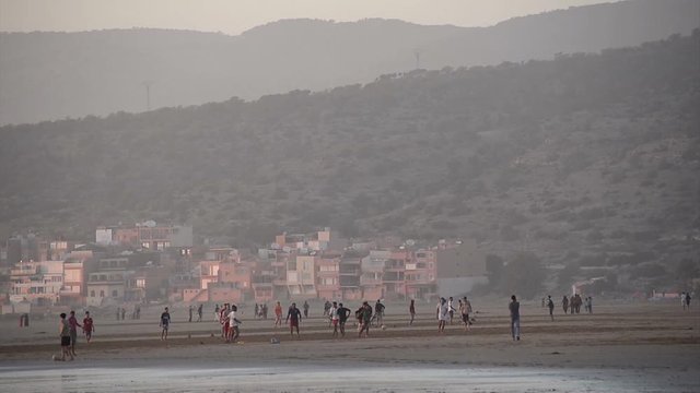 AGADIR, MOROCCO, FEBRUARY 27, 2014. The sand bech with boys and men playing football during the sunset in Agadir, Morocco, on February 27th, 2014.