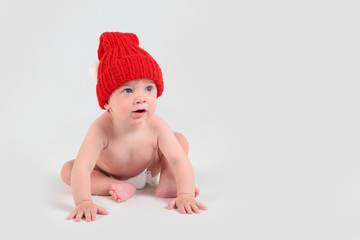 Baby in a red hat and in a diaper on a white background. Free space. Isolated object. Macro photo.