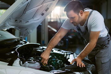 Young auto mechanic examining car oil in a repair shop