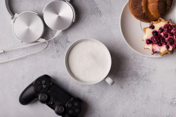 Fototapeta na wymiar Man's breakfast with game. Earphones,coffee, cinnamon bun