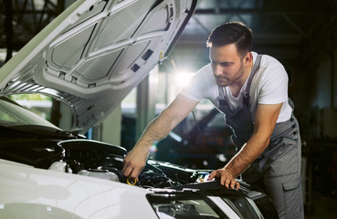 Young auto mechanic examining car oil in a repair shop