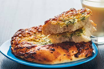 Bread with garlic and cheese and a glass of milk on a dark wooden background.