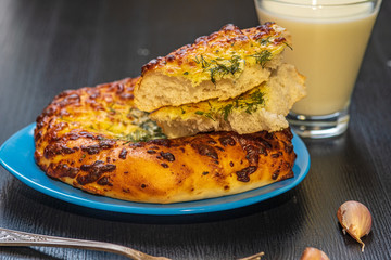 Bread with garlic and cheese and a glass of milk on a dark wooden background.