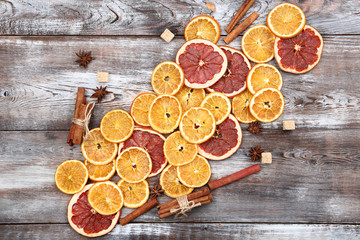 Fototapeta na wymiar Dried citrus fruits with cinnamon, star anise and sugar cubes on brown wooden table