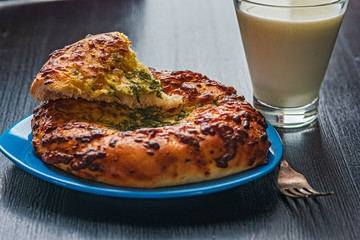 Bread with garlic and cheese and a glass of milk on a dark wooden background.