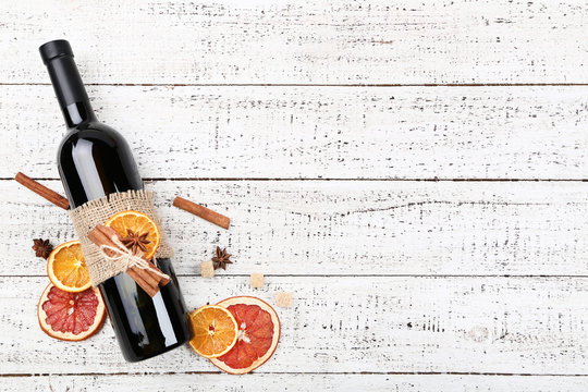 Dried citrus fruits with spices and bottle of wine on white wooden table - Powered by Adobe