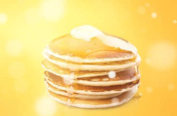 Pancakes with sour cream and honey close-up on a yellow background