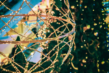 Christmas decoration in shopping centre. Big illuminated christmas decorative ball, traditional Christmas festive spruce tree and colorful lights garlands