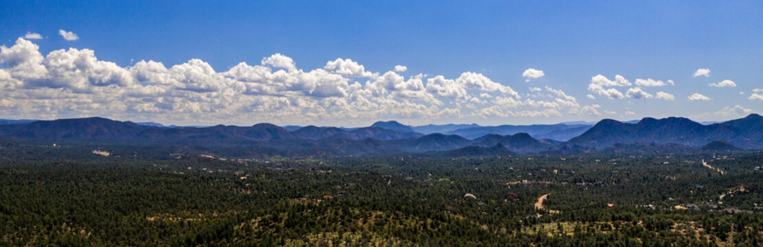 Aerial view of the Tonto National Forest from above the Pine Trailhead in Arizona with blue sky,  white clouds and green ponderosa pines 