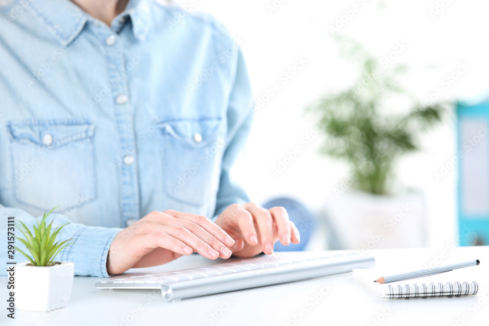 Fototapete female hands typing on computer keyboard with green plant and notepad