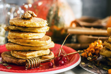 Homemade pancakes stacked on a red plate. Healthy pancakes made with coconut milk and banana, decorated with nuts and fresh berries. Sweet Homemade Stack of Pancakes with Syrup for Breakfast