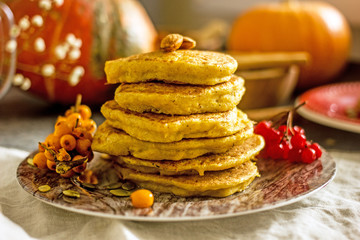 Homemade pancakes stacked on a red plate. Healthy pancakes made with coconut milk and banana, decorated with nuts and fresh berries. Sweet Homemade Stack of Pancakes with Syrup for Breakfast
