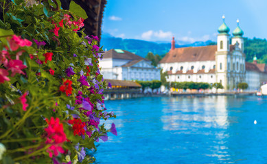 Fototapeta na wymiar Lucerne / Switzerland. Colorful flowers at the Chapel Bridge (Kapellbrücke) with the Jesuit Church in the distance