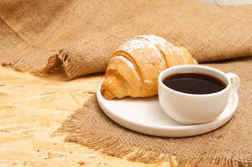 Croissant with a cup of coffee on a plate