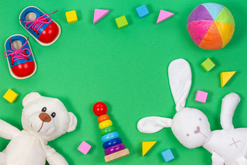 Baby kids toys background with teddy bear, soft plush toys, wooden toys and blocks on light green background.