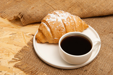 Croissant with a cup of coffee on a plate