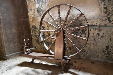 Picture of an antique wooden spinning wheel used to turn animal fleece into yarn, or wool. Spinning wheel is associated with fairy tales &lsquo;Sleeping Beauty&rsquo; is the most well-known spinning wheel story.