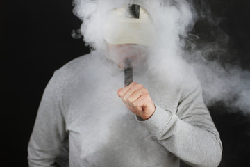 vaping man holding a mod cloud of vapor Black background isolated Selective focus
