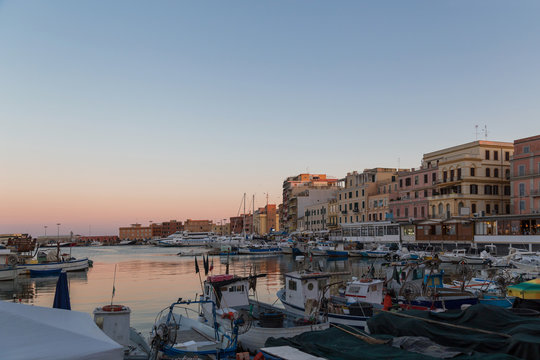 Small picturesque city port at sunset. Anzio, Lazio region, Italy. Fishing boats, small yachts on beautiful evening sky background