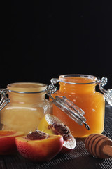Apricots in half and jars of honey on a black background. Out of focus. Still life concept. Copy space.