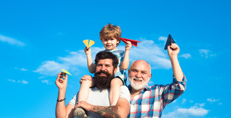Freedom to dream - joyful kid playing with airplane against the sky - vintage effect. Happy grandfather father and grandson with toy paper airplane over sky and clouds background. Generations men.
