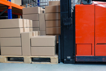 Cardboard boxes and forklift in the warehouse. Close up side view..