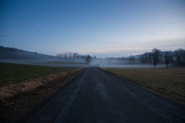 Fototapeta na wymiar A warm winters fog haunts the landscape near Jenksville, NY at sunset