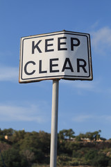 Keep clear road sign in blue sky background, vertical.