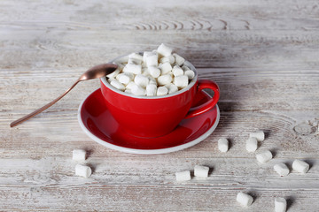 A large red cup of coffee with a spoon and slices of marshmallow. View from above. Copy space. Still life concept.