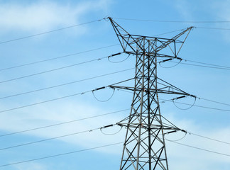 tall metal electricity pylon with multiple cables against a blue cloudy sky