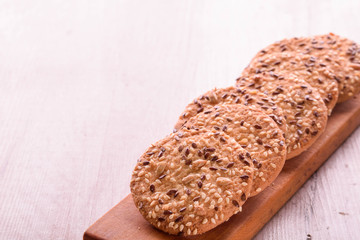 Cookies of sesame seeds, sunflower seeds and other spices on a wooden plate. Bright key