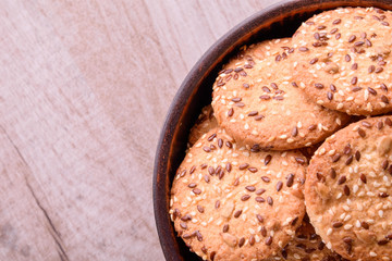 Cookies of sesame seeds, sunflower seeds and other spices on a wooden plate. Bright key