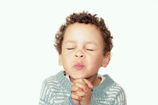 boy praying to God stock image with hands held together with closed eyes and white background stock photo