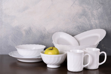  White dishware stacked on a wooden table against grey background on wooden table