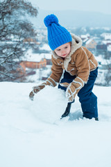 Fototapeta na wymiar Happy child playing with snow on a snowy winter walk. Cute child in frosty winter Park. Winter child. Kid playing with snow in park. Kid winter portrait.