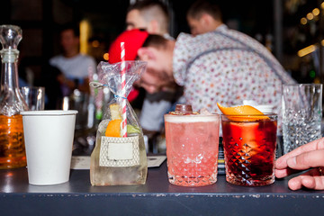bartender is preparing an alcoholic cocktail in a glass glass, he is decorating the drink with flowers