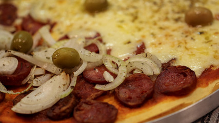 Homemade pizza with cheese, pepperoni, sliced onions and olives