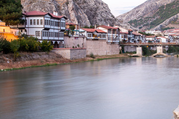 Fototapeta na wymiar Old Ottoman houses and clock tower view by the Yesilirmak River in Amasya City. Amasya is populer tourist destination in Turkey.