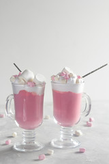 Pink hot chocolate with whipped cream and marshmallows on the grey background. Copy space