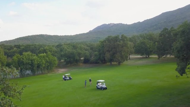 Boogies during a golf game. Flight over a golf course in a forest of ash trees. Escorial monastery