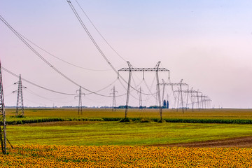 High voltage electricity pylons and transmission power lines on the blue sky background.