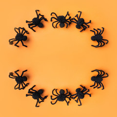 Halloween decorations with black spiders on orange background. Flat lay, top view, copy space.