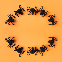 Halloween decorations with black spiders on orange background. Flat lay, top view, copy space.