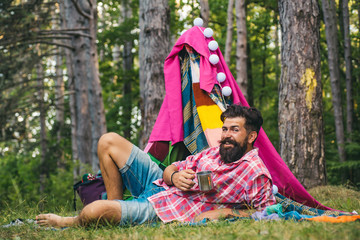 Hut of branches. Rest camping. Story in hovel. Handsome bearded man inside camping tent. Travel recreational outdoor activity concept.