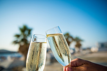 Cheers with two glasses of champagne at the beach with palm trees in the back © Stephane Mingot