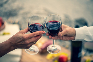 2 hands with 2 glasses of red wine