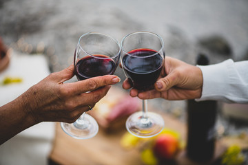 2 hands with 2 glasses of red wine