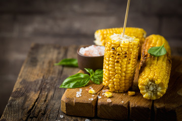 Grilled corn cobs with salt and spices on vintage wood background