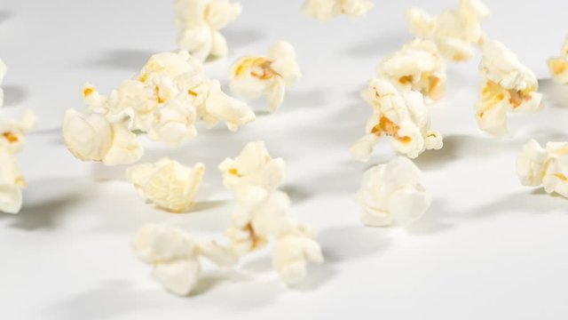Fresh popcorn falling onto a white surface in slow motion