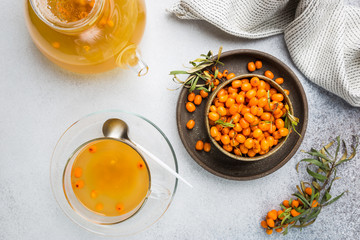 Tea with sea buckthorn on white stone background. top view